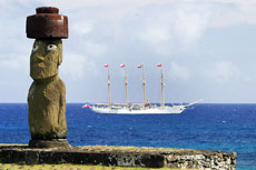 Moai in Hanga Roa, mit dem chilenischen Armeeschiff Buque Escuela Esmeralda im Hintergrund.
